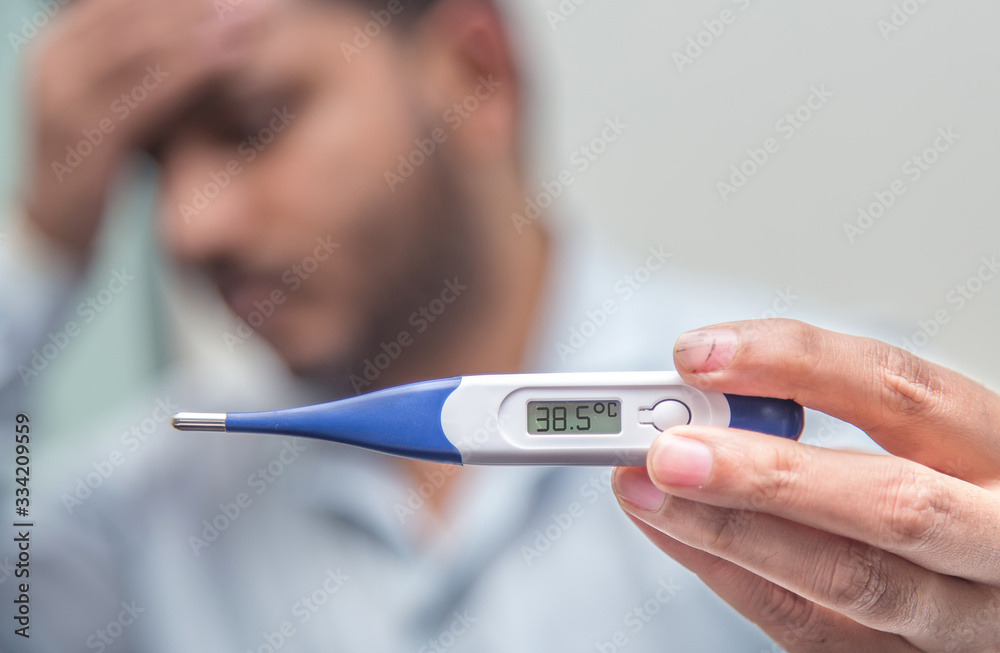 Flu and corona concept: Man is holding a fever thermometer in his hand