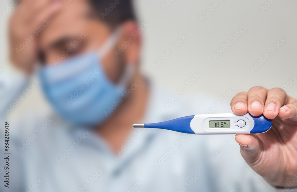 Flu and corona concept: Man is holding a fever thermometer in his hand Flu and corona concept: Man is holding a fever thermometer in his hand