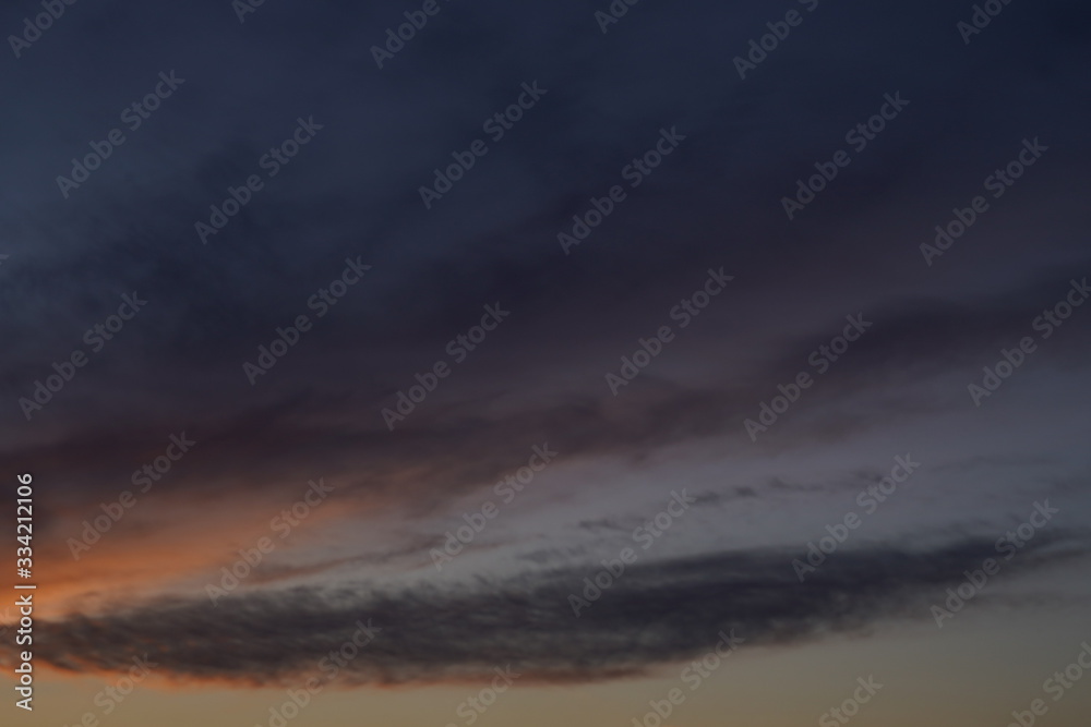 A beautiful evening blue sky at sunset with flaming bright light clouds. Warm evening.