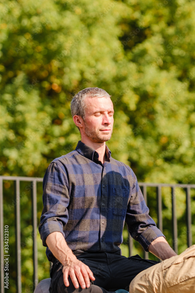 Obraz premium A young man meditates outdoors in a park. 