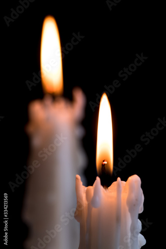 Group of lit candles. White candles burning against a dark background