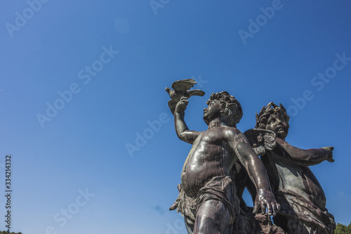 Angels statue and blue sky, Sculpture of cupid,The little angel statue holds a bird in his hand.