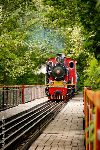 Vintage steam powered railway train. Retro steam locomotive passes through the bridge. Railroad travel, railway tourism. Colored children's train.