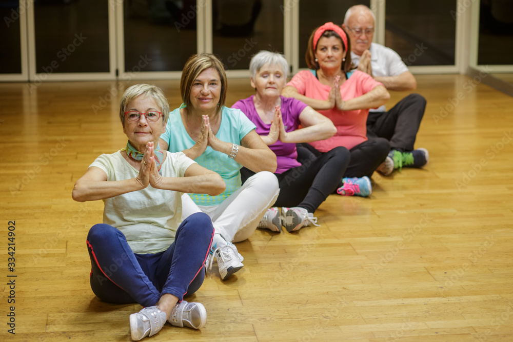 Gruppo di anziani  si dedica allo yoga in palestra
