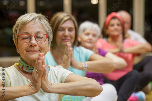 Gruppo di anziani  si dedica allo yoga in palestra photo
