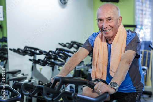 Uomo anziano si allena in una palestra con lo spinning e sorride felice