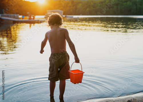 Young boy standing in a lake holding a bucket, Bedford, Halifax, Nova Scotia, Canada