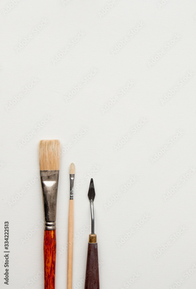 Fototapeta premium Various palette knife and paintbrushes on a white background. Professional brushes with a palette knife isolated on a white background. Space for text.