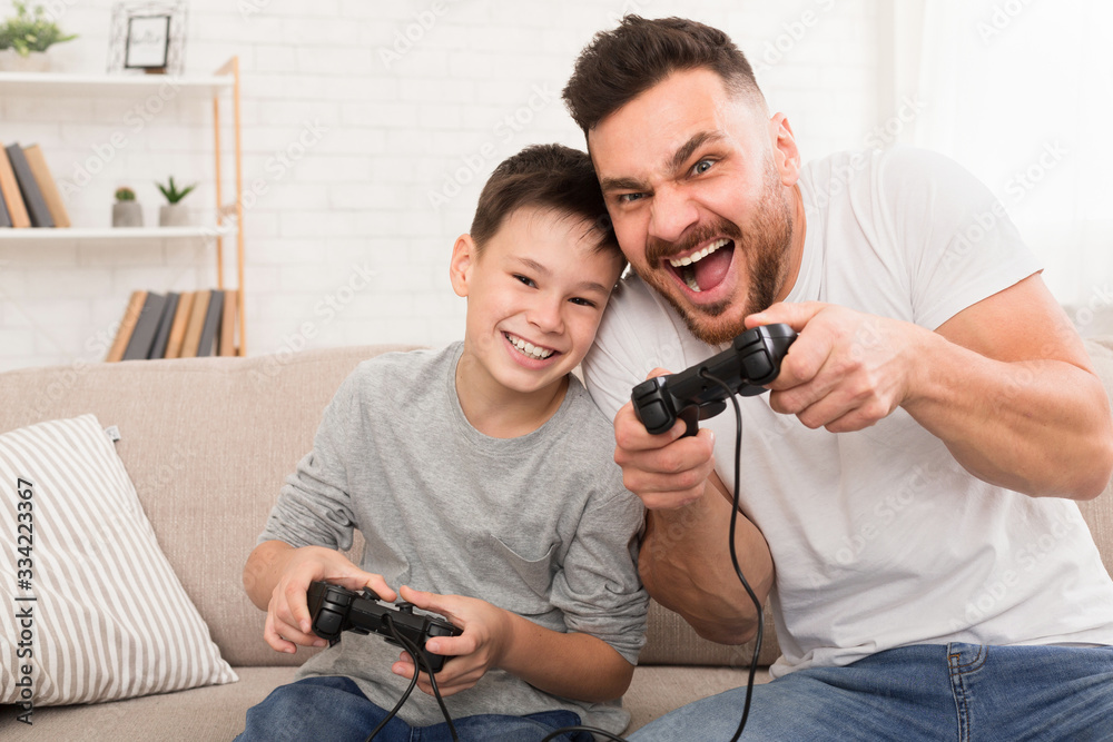 Dad and son with joysticks playing video games at home