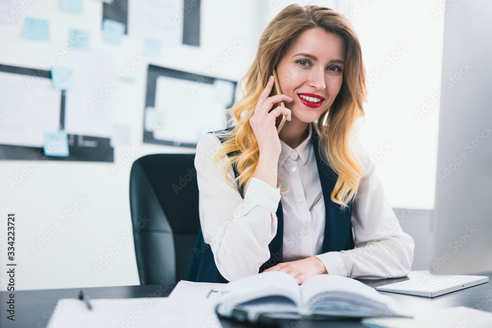 young woman manager with red lipstick works in her modern office, having phone conversation , looks satisfied, multitasking, work concept young woman manager with red lipstick works in her modern office, having phone conversation , looks satisfied, multitasking, work concept