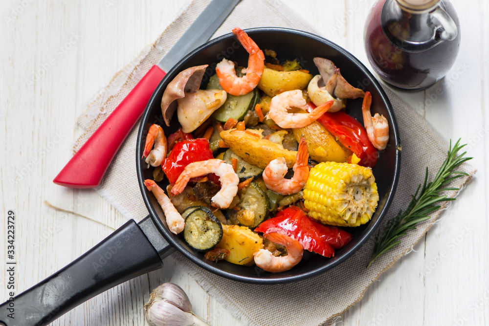 pan with fried vegetables, shrimp and squid with spices