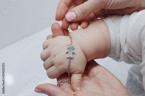 Fototapet Closeup shot of a female putting a cute bracelet on her baby's hand