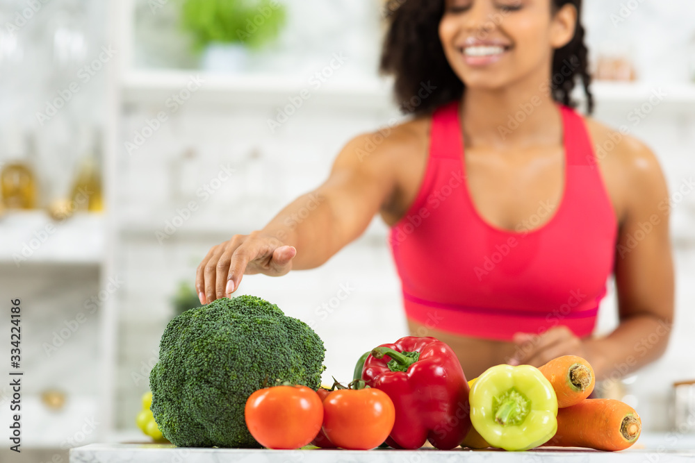 Happy young afro girl preparing vegetable salad