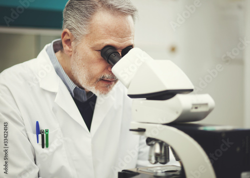 Scientist conducting research looking through microscope © Minerva Studio