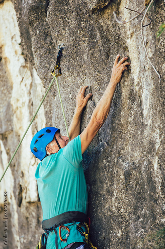 Senior man with a rope climbing on the rock.