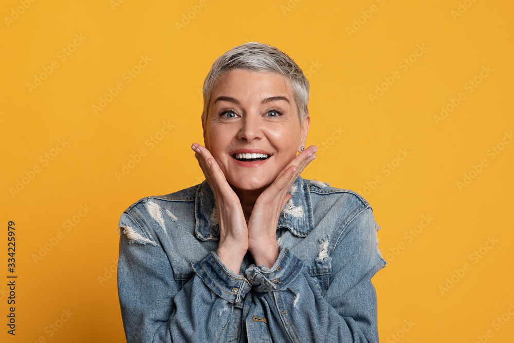 Portrait Of Surprised Middle Aged Woman Touching Her Cheeks In Excitement - obrazy, fototapety, plakaty 