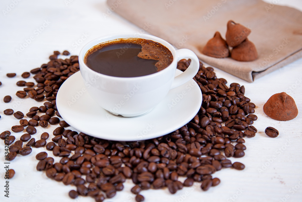 Fototapeta premium White cup of coffee stands on coffee beans