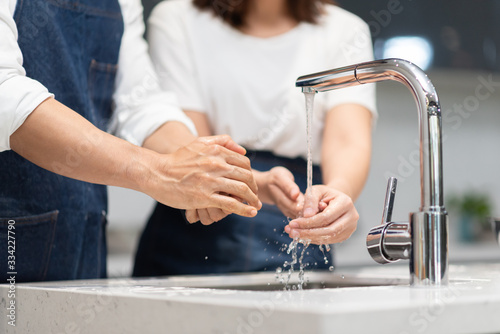 Asian couple washing hands with foam soap before cooking at home.