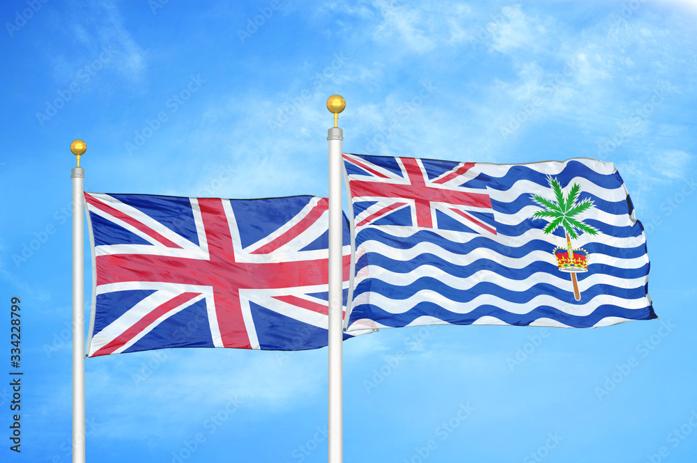 United Kingdom and British Indian Territory two flags on flagpoles and blue cloudy sky United Kingdom and British Indian Territory two flags on flagpoles and blue cloudy sky