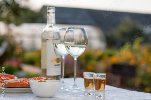 Slow motion of middle aged sommelier mix and controls the color of white wine poured in transparent glass on a scenic vineyard panoramic background (close up)