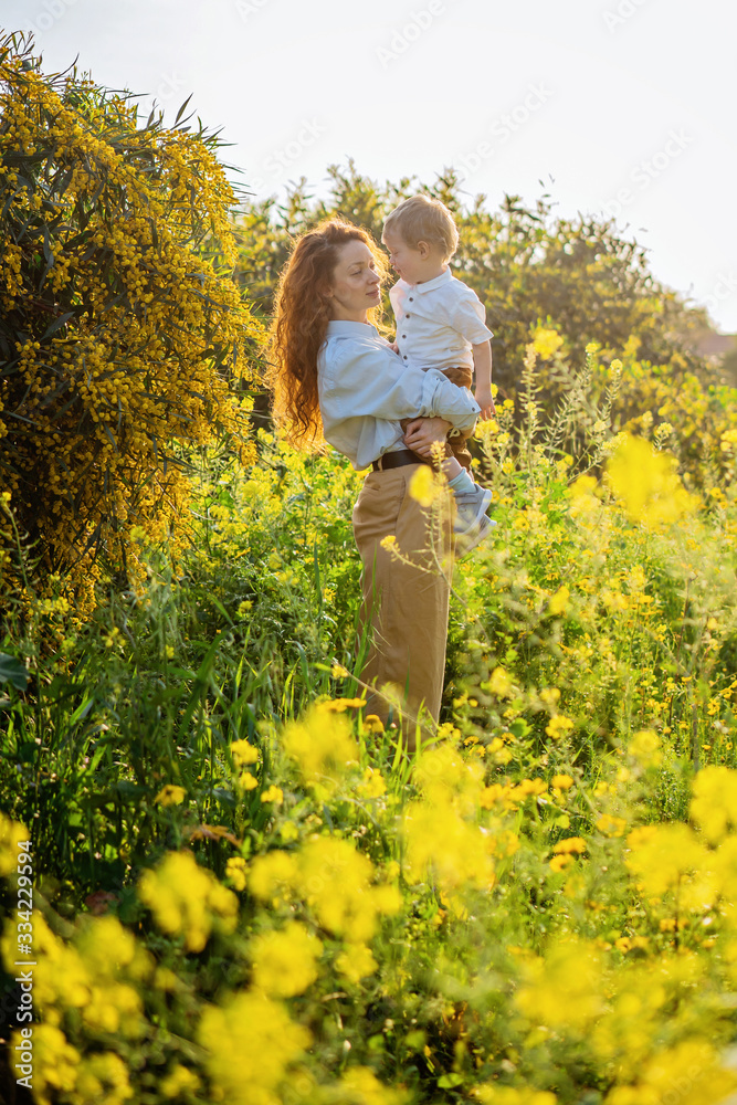 Mother and child enjoy early spring in blooming yellow flowers field or garden eco friendly in harmony with nature. Happy Mothers day holiday concept. Earth day family celebration seasonal greeting