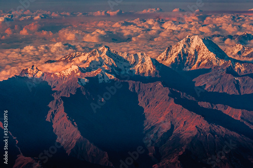 Viewed from above the Andes mountains in clouds and snow at their top at sunset