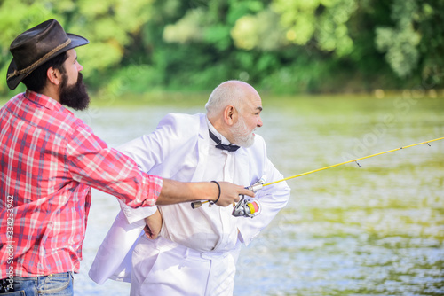 early retirement. hobby and recreation. two fishermen with fishing reel. mature man fisher celebrate retirement. retired businessman. male friendship. family, granddad and drandson fishing photo