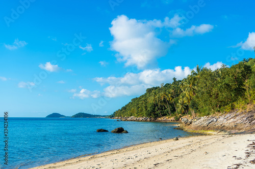 Sandy beach of a paradise deserted tropical island. Palm trees overhang on the beach. White sand. Blue water of the ocean. Rest away from people