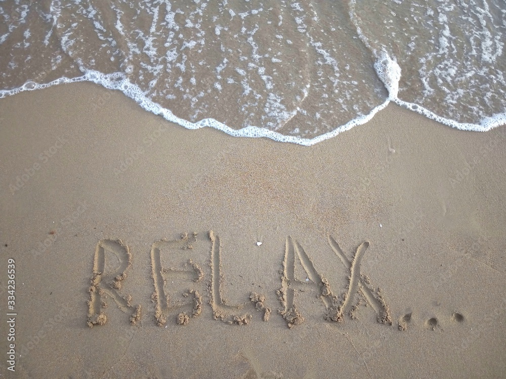 Fototapeta premium Title Relax... on a sandy beach with a sea wave above. Vacation concept.