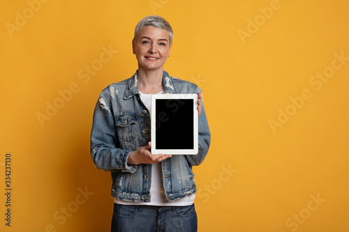 Beautiful middle aged woman showing digital tablet with blank black screen