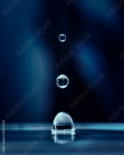 goccie d'acqua che si inseguono su sfondo blu photo