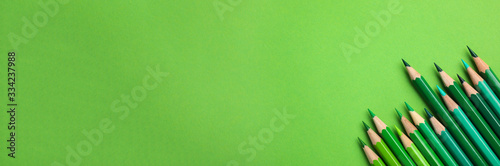 Color pencils on green background, flat lay with space for text. Banner design