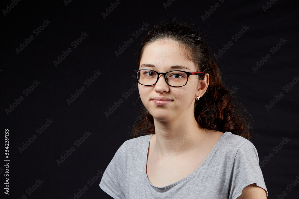 Fototapeta premium portrait of a shy young girl with glasses on the dark background