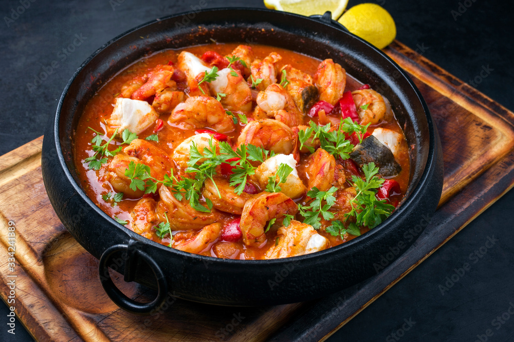 Traditional American fish stew cioppino with prawns, and fish as top view in a modern design cast-iron roasting dish Traditional American fish stew cioppino with prawns, and fish as top view in a modern design cast-iron roasting dish