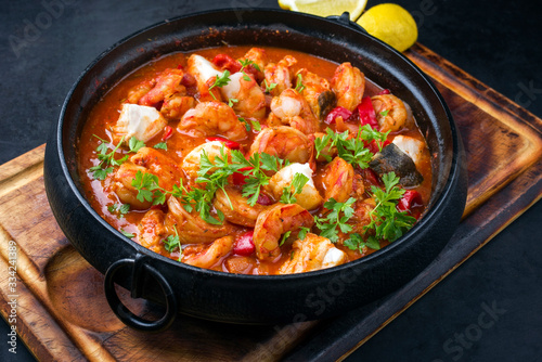 Traditional American fish stew cioppino with prawns, and fish as top view in a modern design cast-iron roasting dish