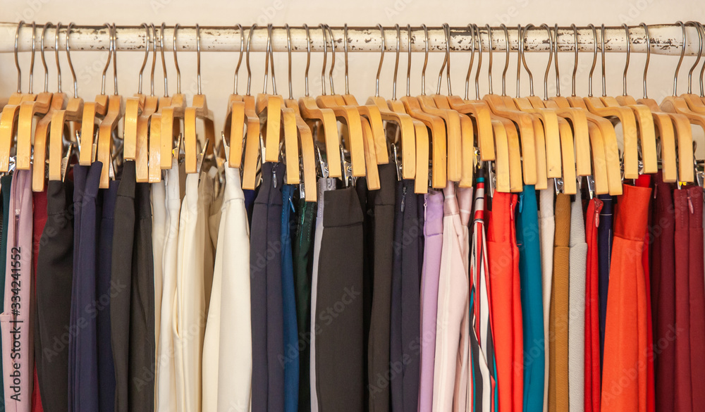 Clothes hang on a shelf in clothes store. Clothes for women hanging on hangers in home closet or shopping mall for store sale concept. Clothes hang on a shelf in clothes store. Clothes for women hanging on hangers in home closet or shopping mall for store sale concept.