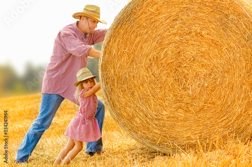Canvas-taulu Father with a child play kittens a haystack on the field