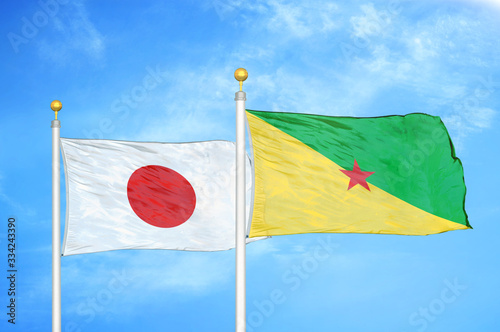 Japan and French Guiana two flags on flagpoles and blue cloudy sky photo