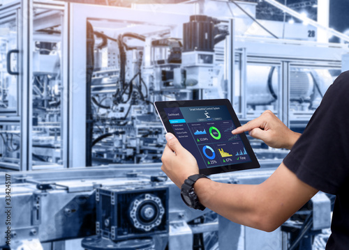 Smart industry control concept.Hands holding tablet on blurred automation machine as background photo