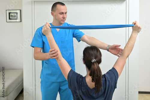 A young male physiotherapist helping a girl with stretching exercises
