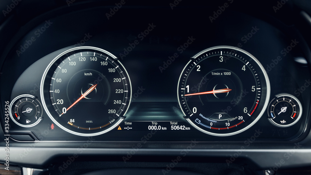 Glowing beautiful dashboard of a modern expensive car. The interior of the car. The foreground is blurred. Modern car interior details. Car detailing. Selective focus