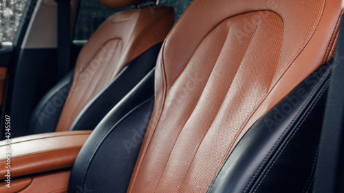 Black and brown leather car interior. Modern car illuminated dashboard. Luxurious car instrument cluster. Close up shot of automobile instrument panel. Modern car interior dashboard and steering wheel