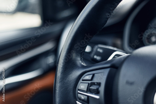 Multimedia leather steering wheel in a modern expensive car. Black and brown leather car interior. Perforated leather steering wheel. Modern car interior details. Selective focus