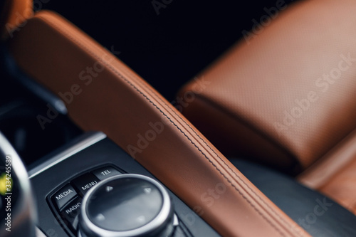 Black and brown leather car interior. Modern car illuminated dashboard. Luxurious car instrument cluster. Close up shot of instrument panel. Modern car interior dashboard. Electric hand brake