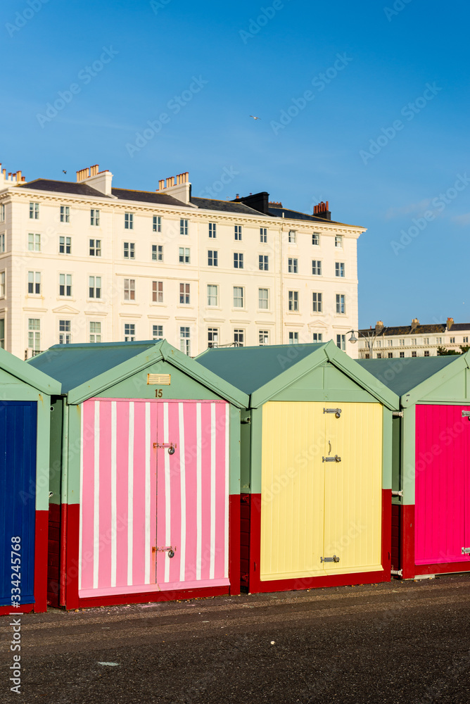 Naklejka premium Hove beach huts against the backdrop of Regency buildings that line the seafront.