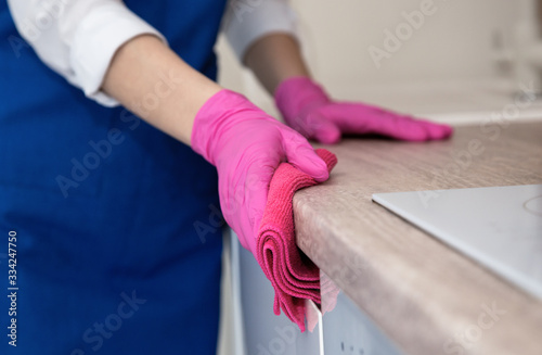 Girl in pink rubber gloves washes the apartment kitchen. photo