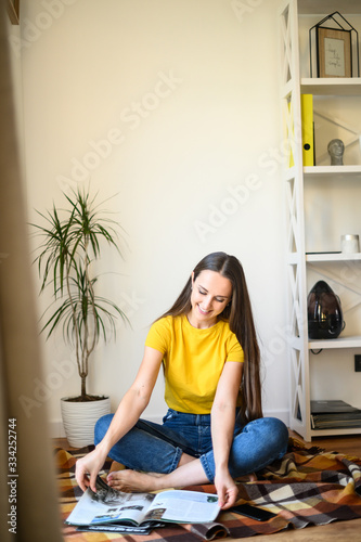Fototapeta Naklejka Na Ścianę i Meble -  Young attractive girl reads magazines at home