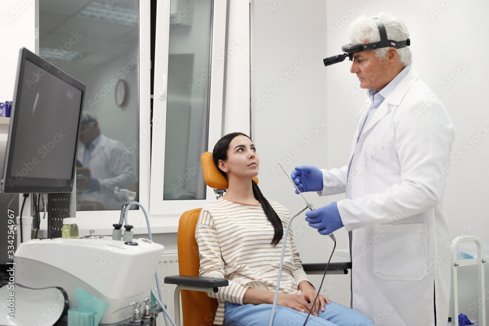 Obraz premium Doctor examining patient with modern equipment before nasal surgery in clinic
