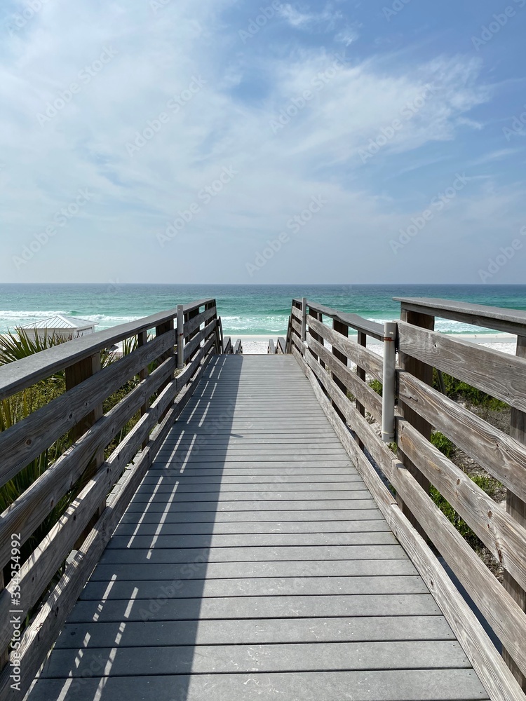 Bridge on white sand beach leading to emerald Gulf of Mexico water