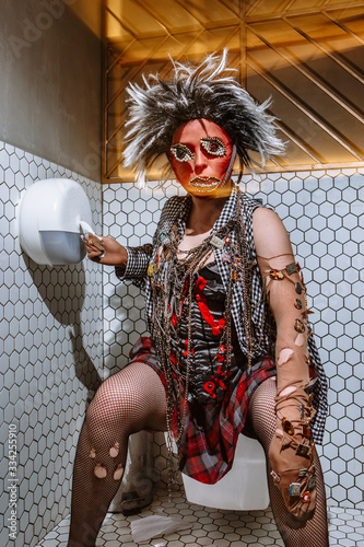 Girl in the toilet, in Vivienne Westwood style clothes with a stocking on her head